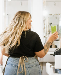 smiling hair stylist holding divi product in their hand